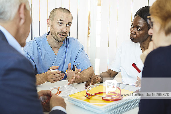 Männliche und weibliche Ärzte diskutieren mit Mann und Frau während eines Klinikbesuchs