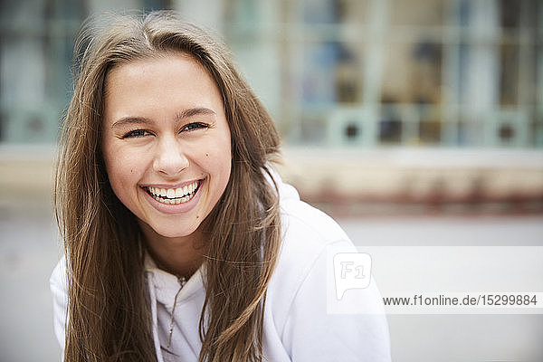Portrait of smiling teenage girl sitting in schoolyard