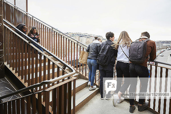 Teenage male and female friends on staircase in city