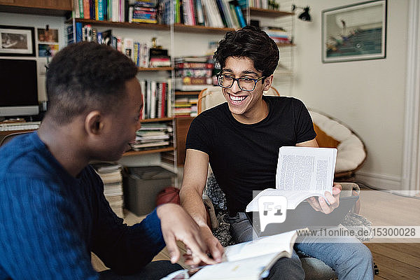 Cheerful friends studying while sitting in living room at home