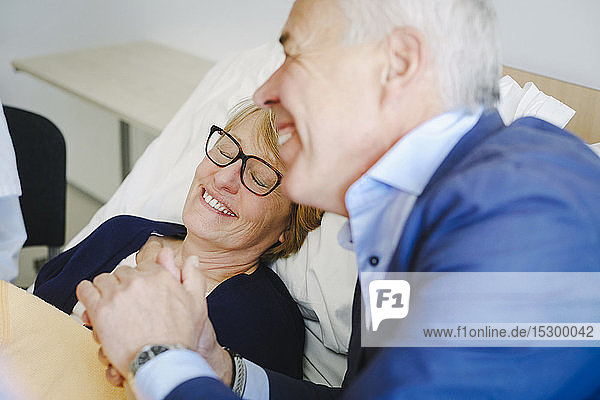 Lächelnde Frau mit geschlossenen Augen vom Seniorpartner auf der Krankenhausstation