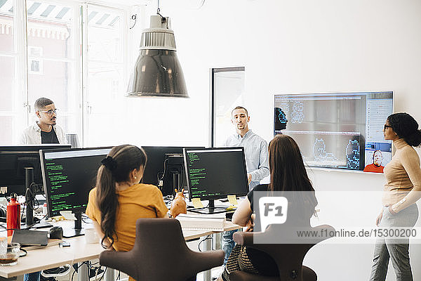 Computer hackers discussing during presentation in office