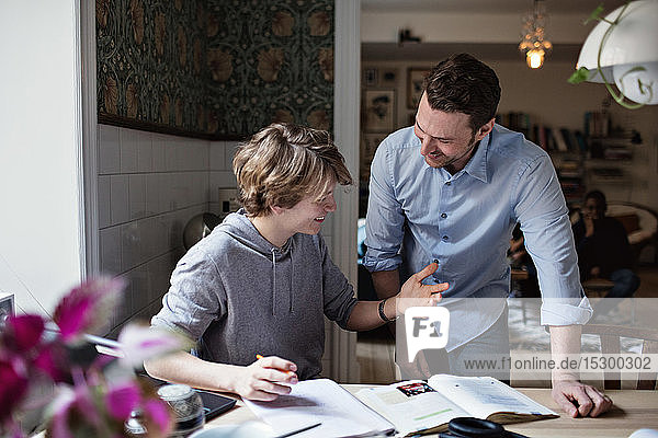 Lächelnder Sohn bedankt sich beim Vater für seine Hilfe bei den Hausaufgaben zu Hause