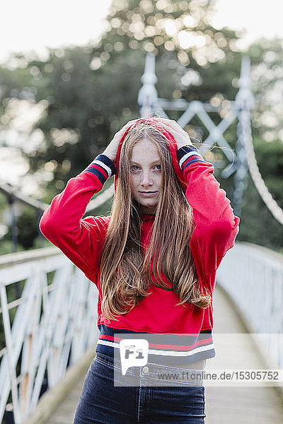 Portrait of teenage girl on a bridge  red hoodie sweater
