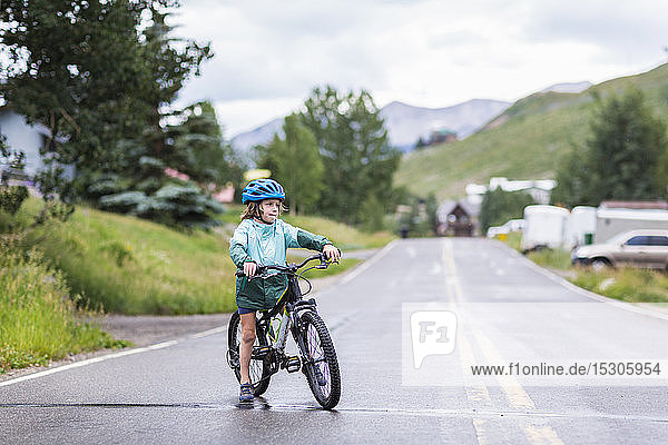 5 Jahre alter Junge mit seinem Mountainbike auf regnerischer Straße