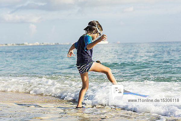 5 Jahre alter Junge beim Anlegen seiner Schwimmflossen am Strand