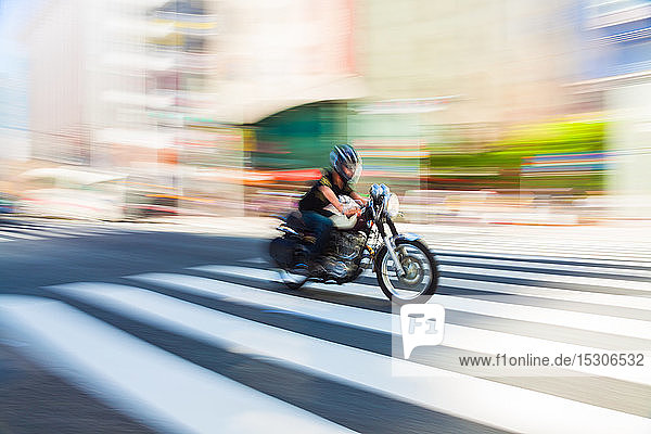 Bewegungsunscharfe Aufnahme eines Motorrads bei Geschwindigkeit auf einem Fußgängerüberweg in Tokio  Japan.