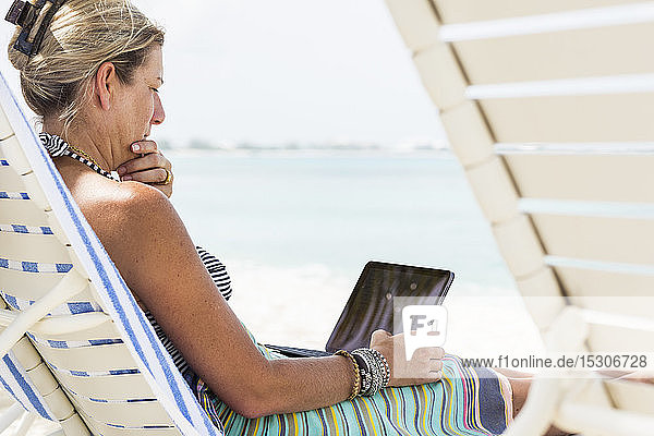 erwachsene weibliche Führungskraft mit Laptop am Strand