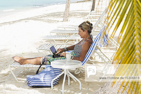 erwachsene weibliche Führungskraft mit Laptop am Strand