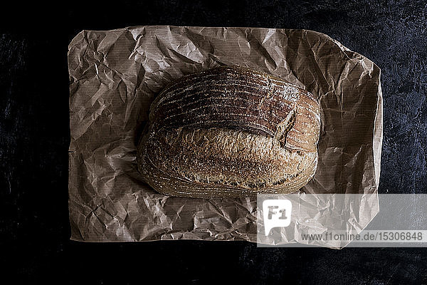 Ein frischer Laib gebackenes Brot auf einer braunen Papiertüte.