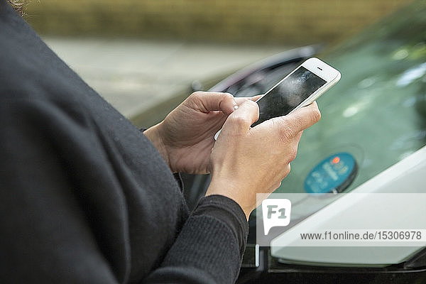 Close up woman using smart phone to access car share