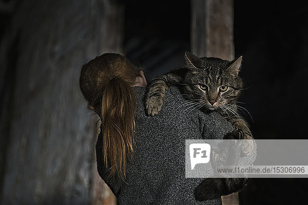 Mädchen hält Katze über der Schulter