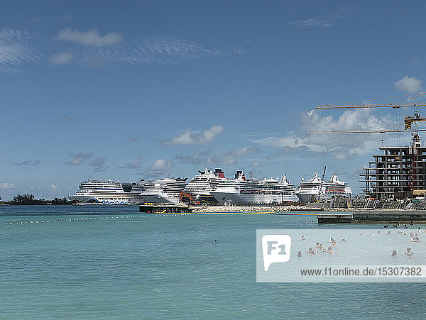 Touristen schwimmen im sonnigen Meer mit Kreuzfahrtschiffen im Hintergrund  Nassau  Bahamas