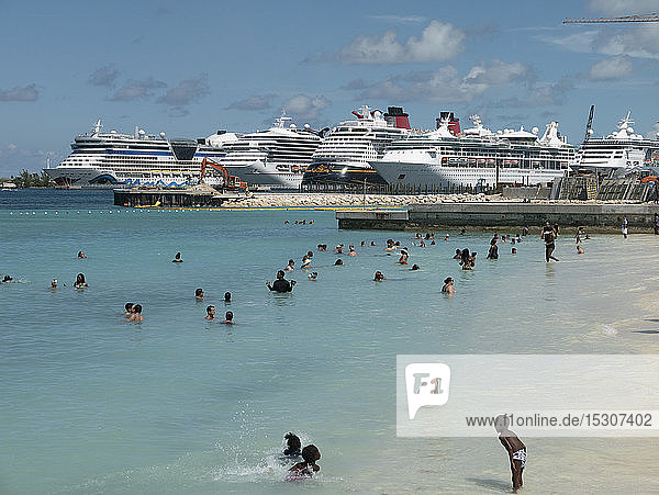 Tourists swimming in sunny ocean with cruise ships in background  Nassau  Bahamas
