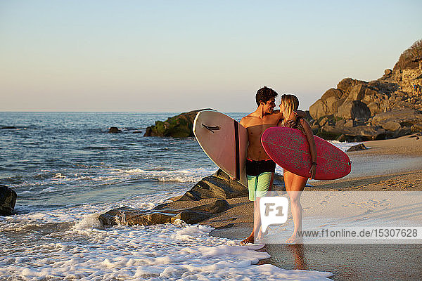 Junges  zärtliches Paar mit Surfbrettern am sonnigen Strand  Sayulita  Nayarit  Mexiko