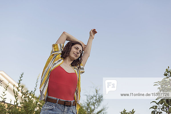 Carefree woman stretching arm overhead