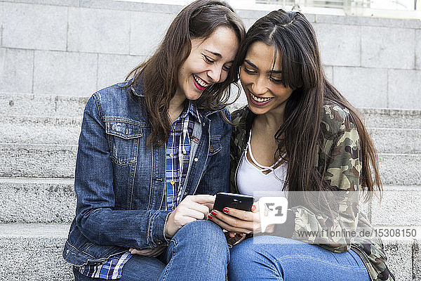 Smiling woman using smartphone  sitting on steps