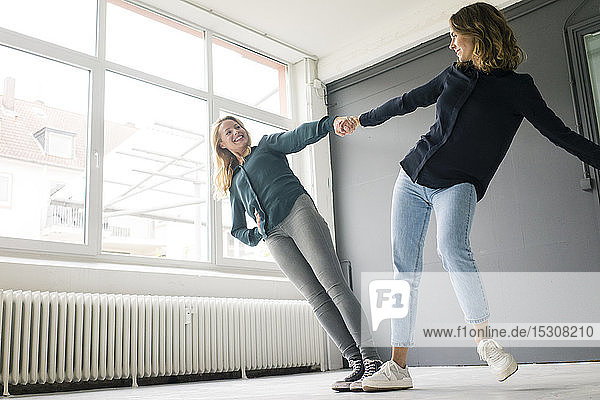 Two young women supporting each other playfully