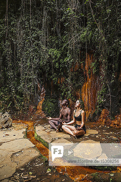 Couple meditating at a waterfall