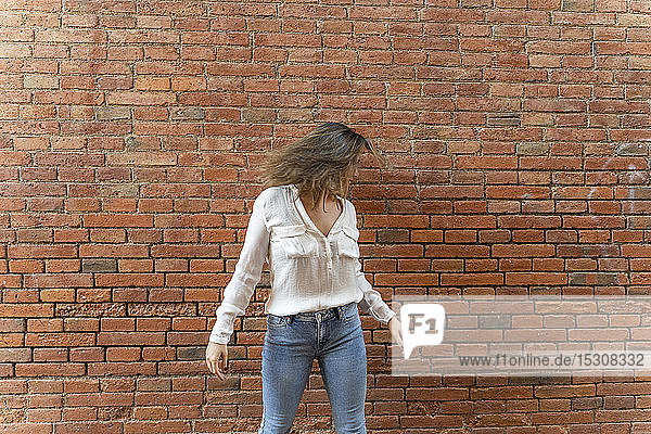 Portrait of youngwoman in front of a brick wall  shaking her head