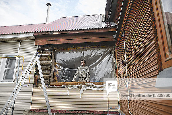 Mann repariert die Fenster seines Hauses