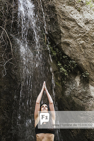 Woman practising yoga at waterfall tree position