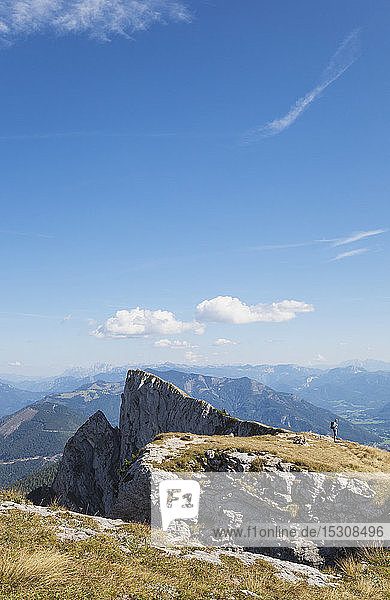 Distant view of hiker standing on Spinnerin peak against blue sky