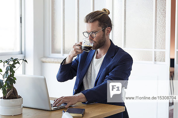 Businessman with laptop and cup of coffee at table