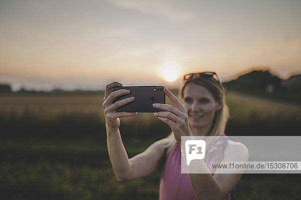 Frau macht bei Sonnenuntergang ein Selfie