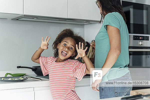 Portrait of happy girl cooking with mother in kitchen