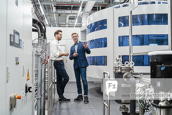 Zwei Geschäftsleute im Gespräch in einer modernen Fabrik