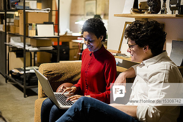 Geschäftsmann und Geschäftsfrau sitzen im Büro mit Laptop auf der Couch