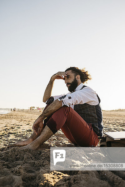 Thoughtful well dressed man sitting on a beach