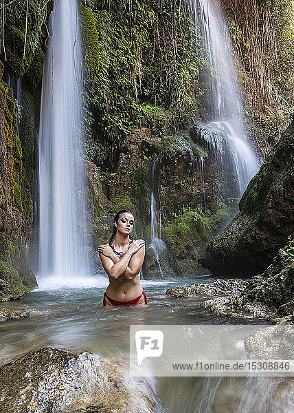 Junge Frau posiert mit verbranntem Körper im Wasserfall