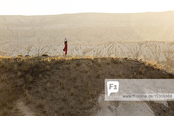 Woman doing a yoga exercise in rocky landscape at dusk  Goreme  Cappadocia  Turkey