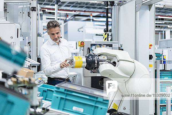 Businessman examining assembly robot in a factory