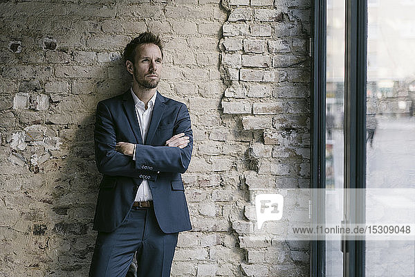 Portrait of businessman leaning against brick wall