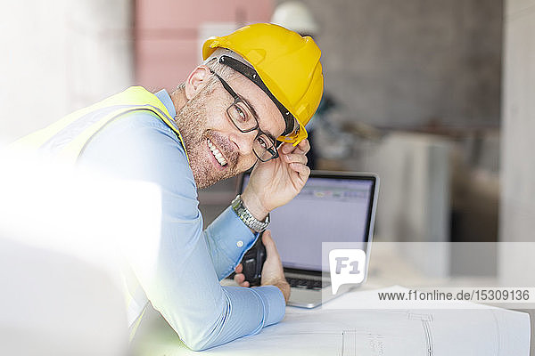 Architect using laptop at construction site  looking at camera