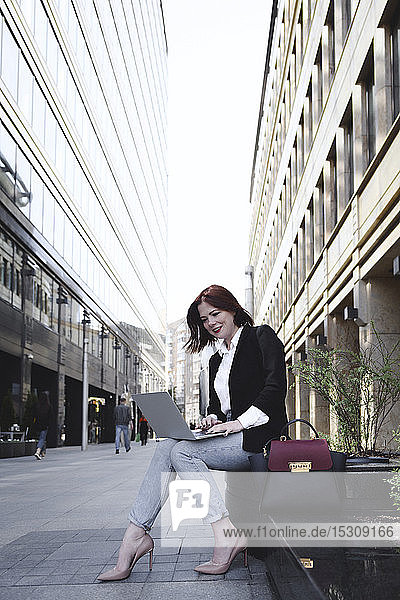 Geschäftsfrau in der Stadt  die einen Laptop benutzt