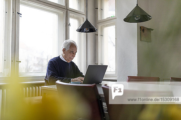 Älterer Mann benutzt Laptop zu Hause auf dem Tisch