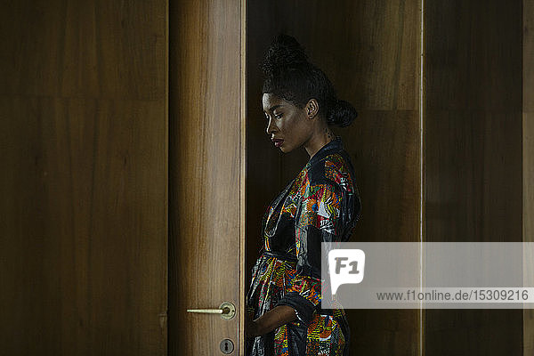 Portrait of chic woman wearing patterned dress at a wooden door