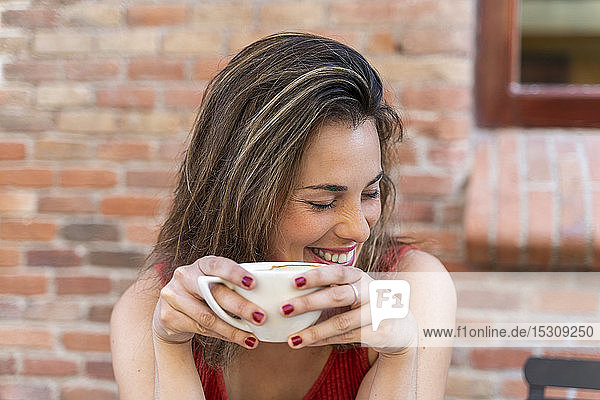 Porträt einer lachenden jungen Frau mit Tasse Kaffee