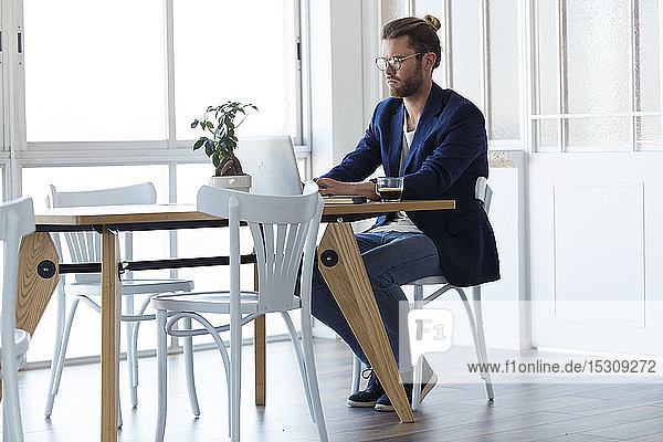 Geschäftsmann mit Laptop am Tisch im modernen Büro