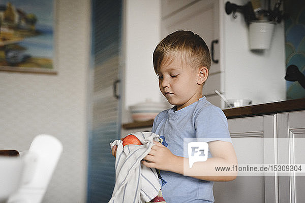 Porträt eines kleinen Jungen beim Pfirsichtrocknen mit Küchentuch