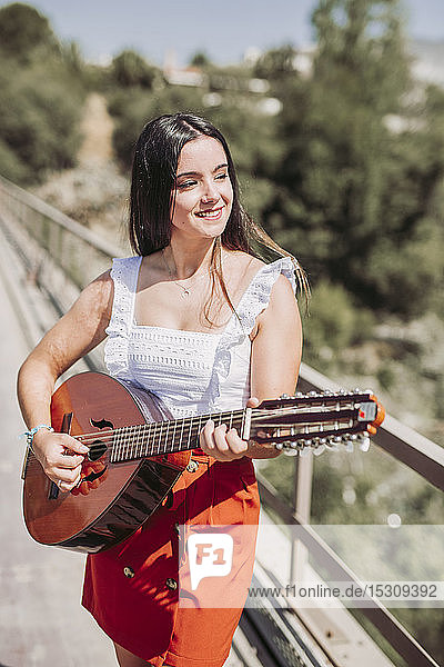 Junge Frau spielt Gitarre  steht auf der Brücke