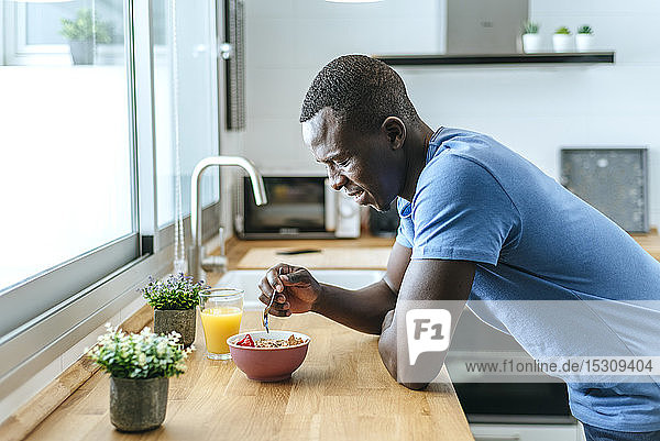 Junger Mann frühstückt zu Hause in der Küche