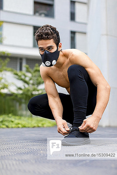 Young athlete tying shoes wearing breathing mask