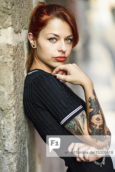 Portrait of red-haired tattooed woman outdoors