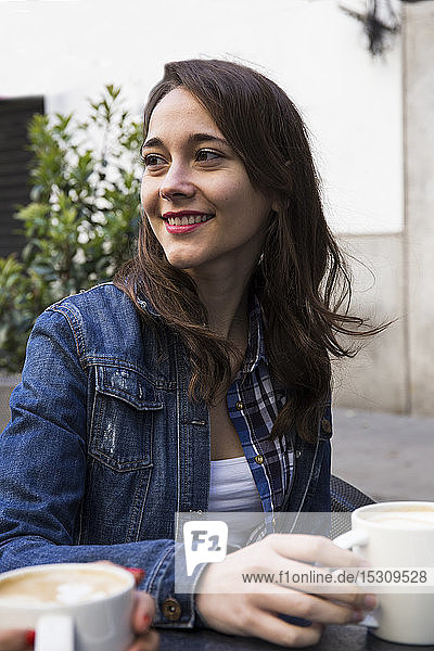 Glückliche junge Frau mit einer Tasse Kaffee in einem Straßencafé in Madrid  Spanien