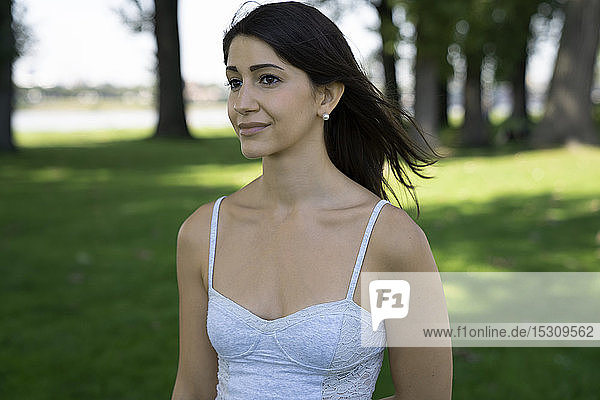 Porträt einer jungen Frau in weißem Top in einem Park im Sommer